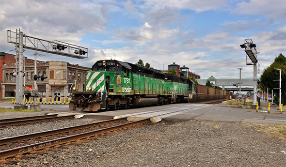 The Federal Railroad Administration has announced a summer safety push focusing on grade crossing safety. Here a BNSF coal train rumbles over a road/rail crossing in downtown Auburn, Washington on July 9th, 2016. Image © by Nikki Burgess; all right reserved.
